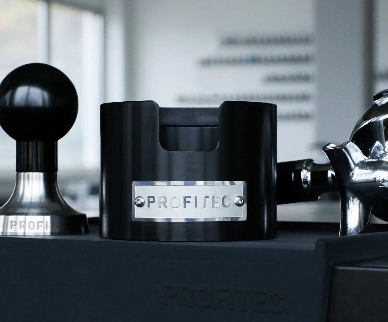 Profitec Tamperstation in black anodized aluminum with tamper and portafilter.